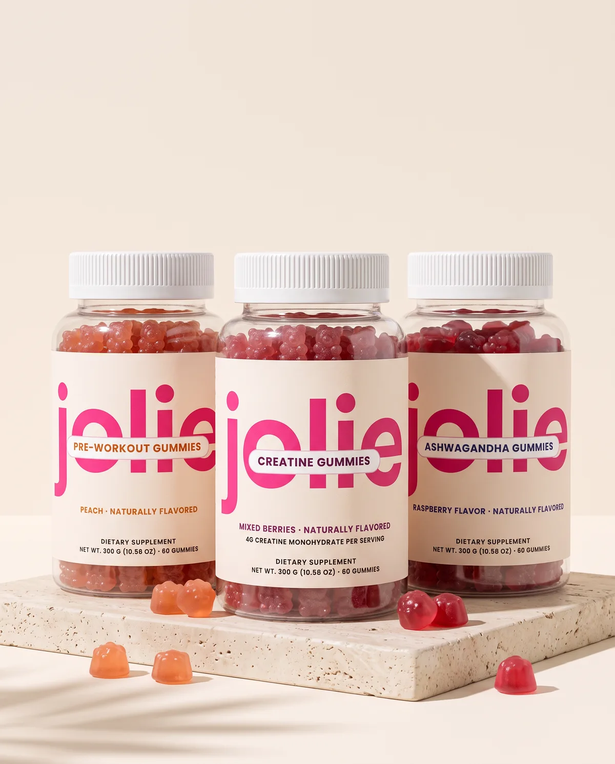 Three jars of jolie gummies on a travertine stone
